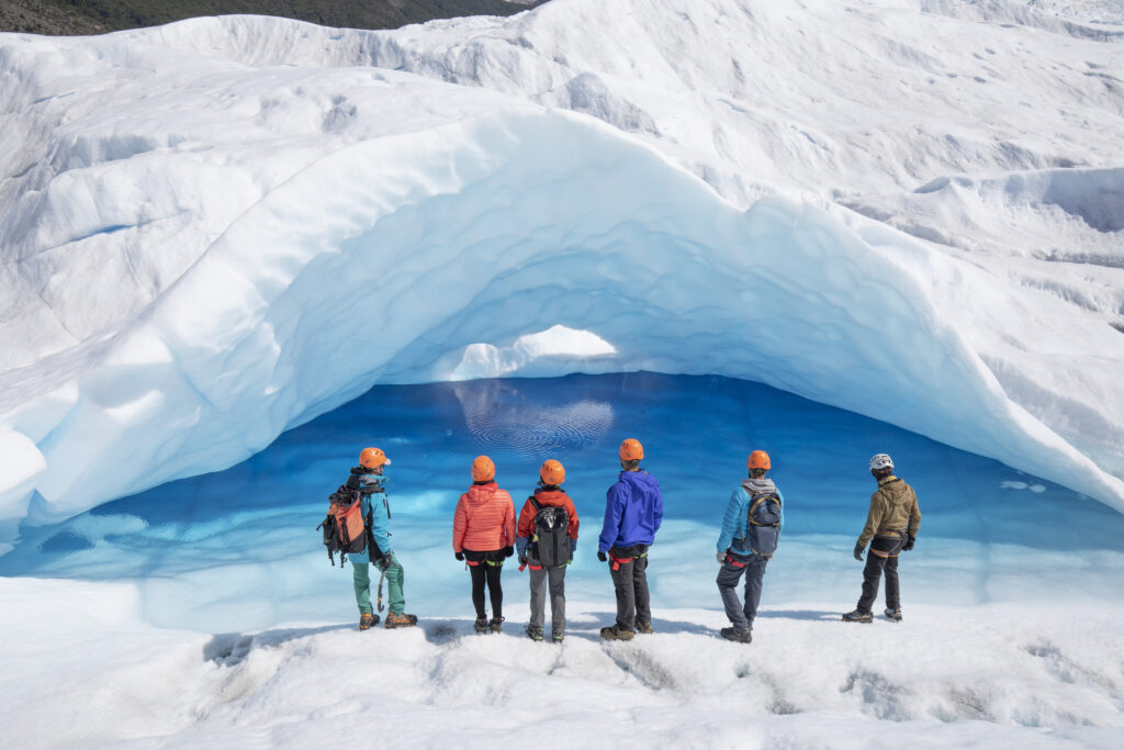 Grupo con cascos frente a una cueva de hielo azul en el trekking Big Ice