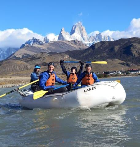 Grupo festejando en un bote de rafting con el Fitz Roy de fondo